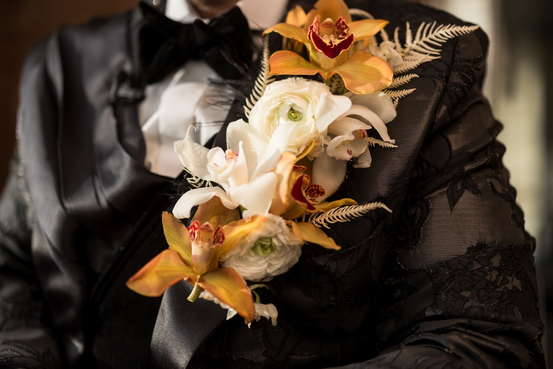 Oversized cymbidium and ranunculus lapel piece on a black brocade tuxedo