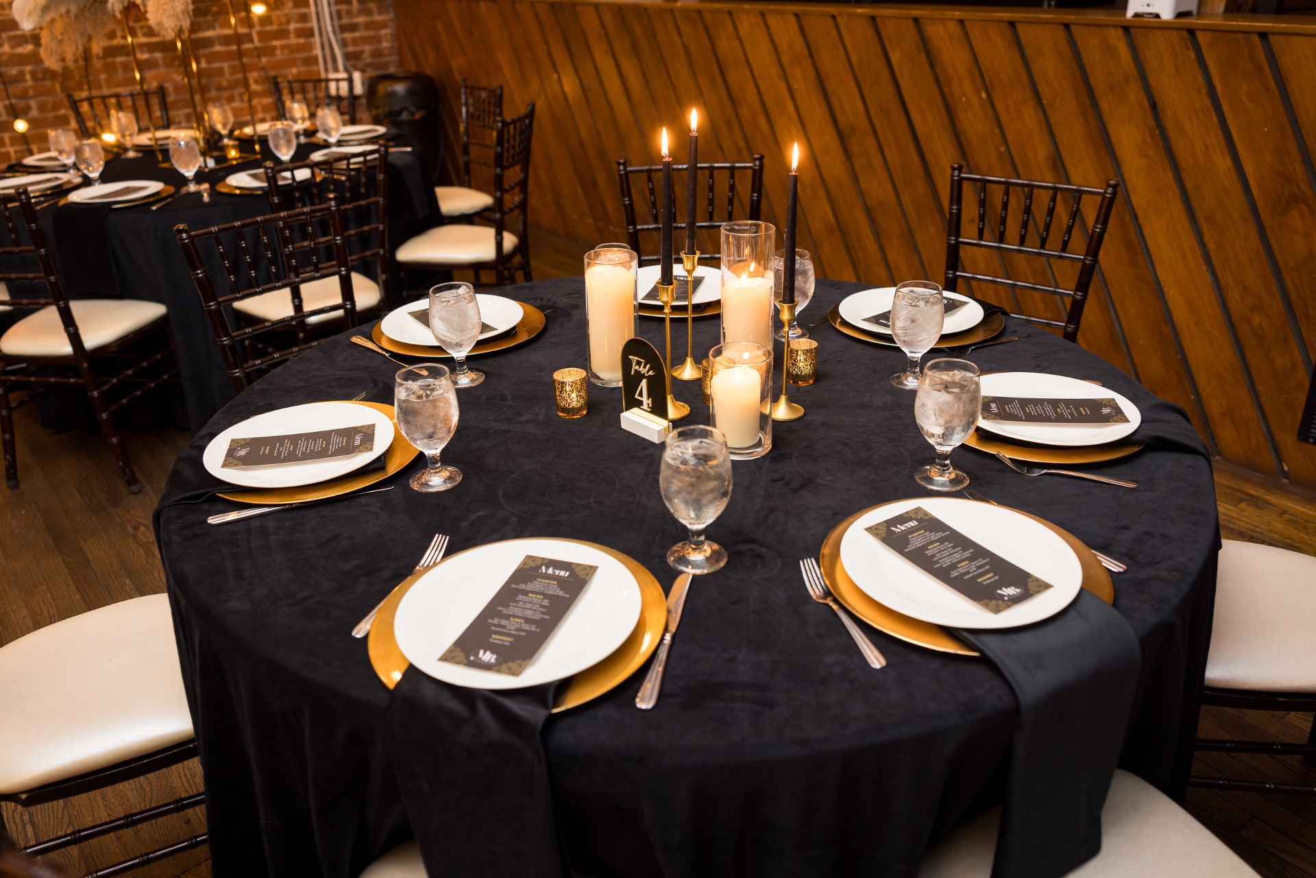 Black velvet reception round with gold chargers, taper candles and gilded menu cards