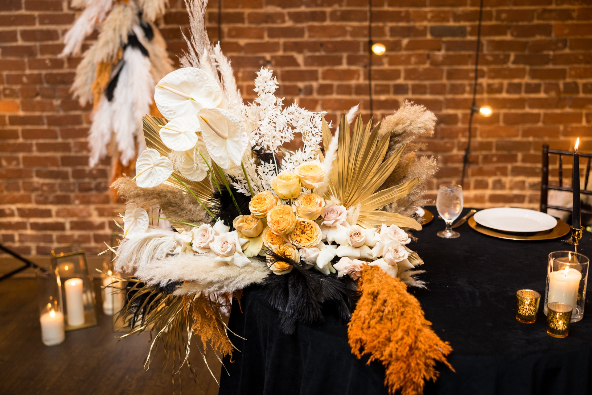 Sweetheart table arrangement of anthurium, garden roses, pampas and gilded palms on black velvet