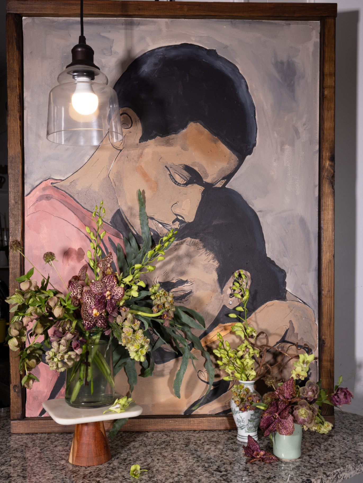 Floral grouping arranged in front of a portrait painting under a pendant light