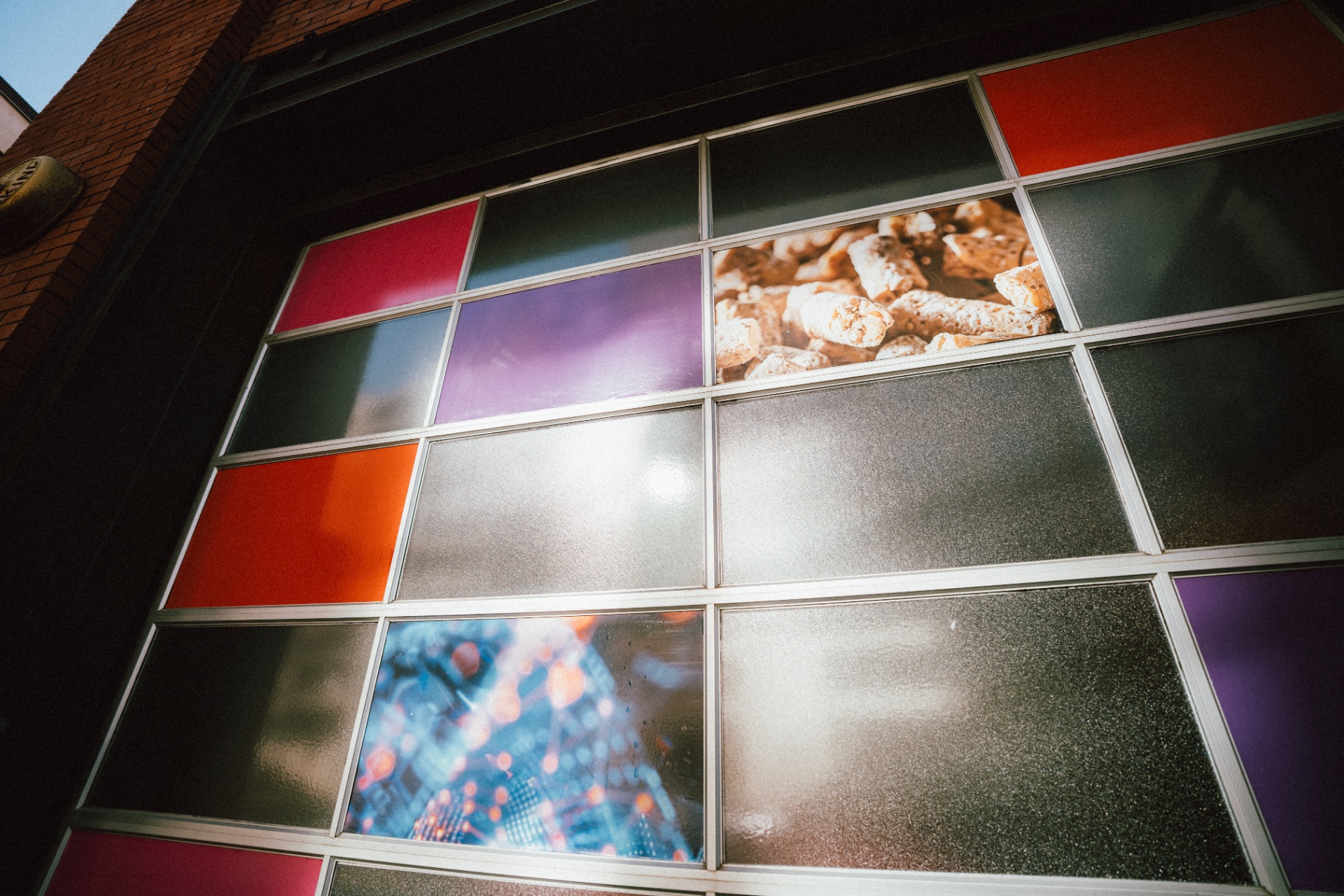 Color-blocked window facade in crimson, plum and orange with brand imagery