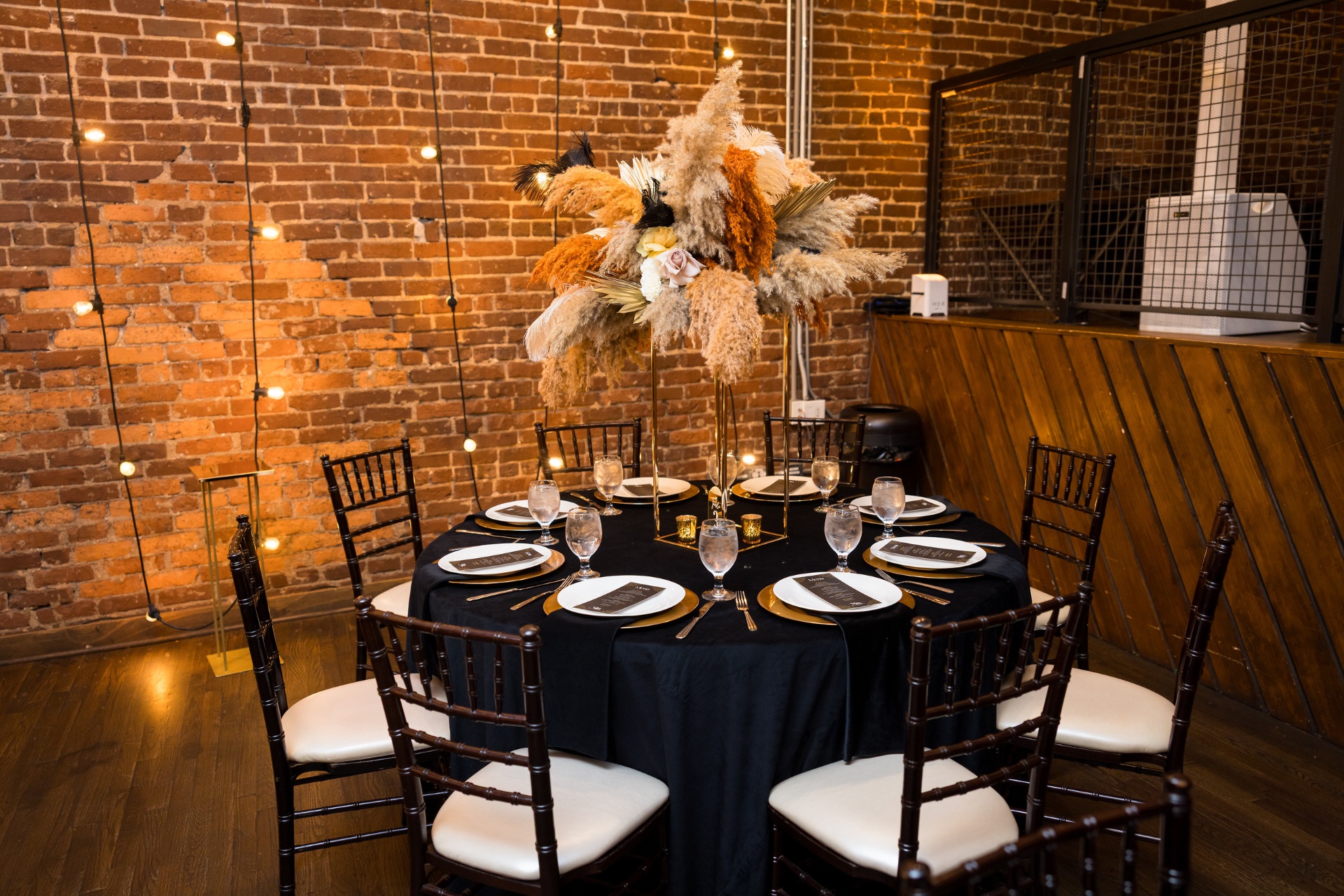 Tall pampas, dried palm and feather centerpiece on a black velvet round in a brick loft