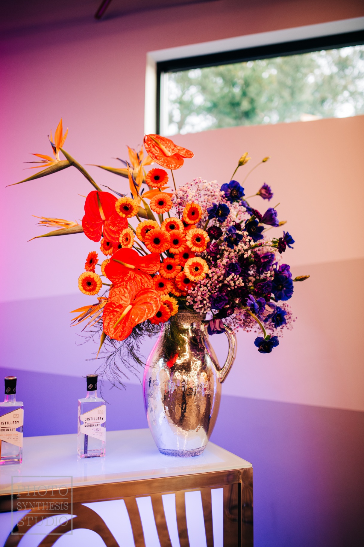 Saturated orange and indigo arrangement with bird of paradise in a mercury pitcher